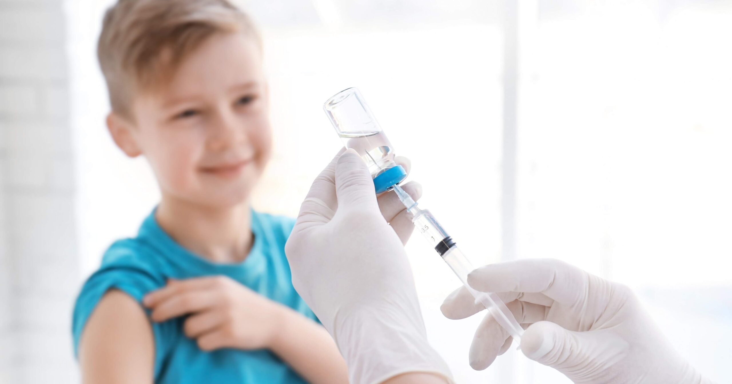 Doctor filling syringe with medicine and child on background. Vaccination day