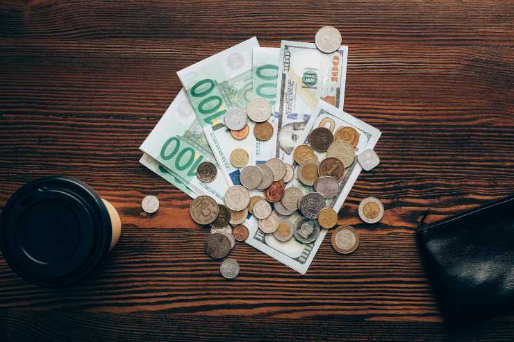 Diverse banconote e monete di varie valute su un tavolo - foto Depositphotos - PalermoLive.it