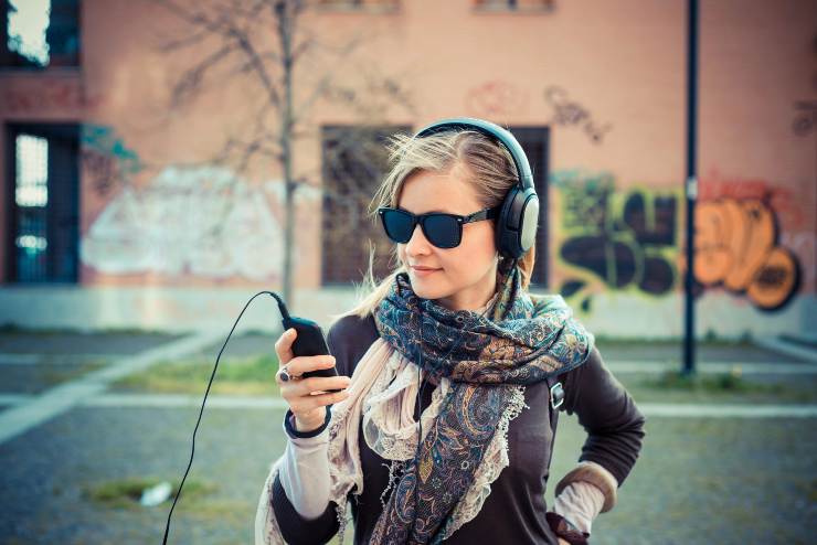 Giovane donna felice di ascoltare musica con le cuffie - foto Depositphotos - PalermoLive.it